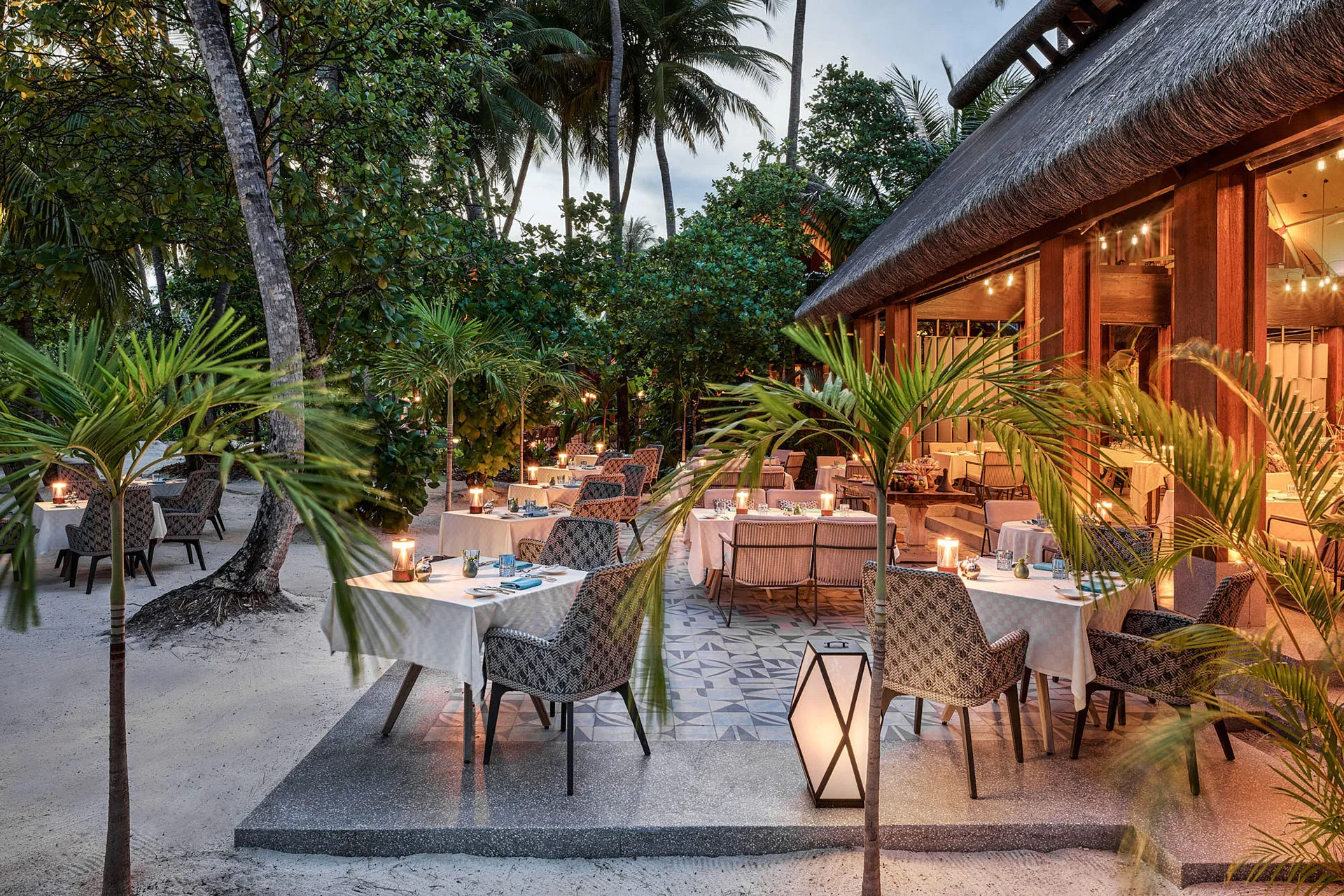 Mehrere Restauranttische in tropischem Garten